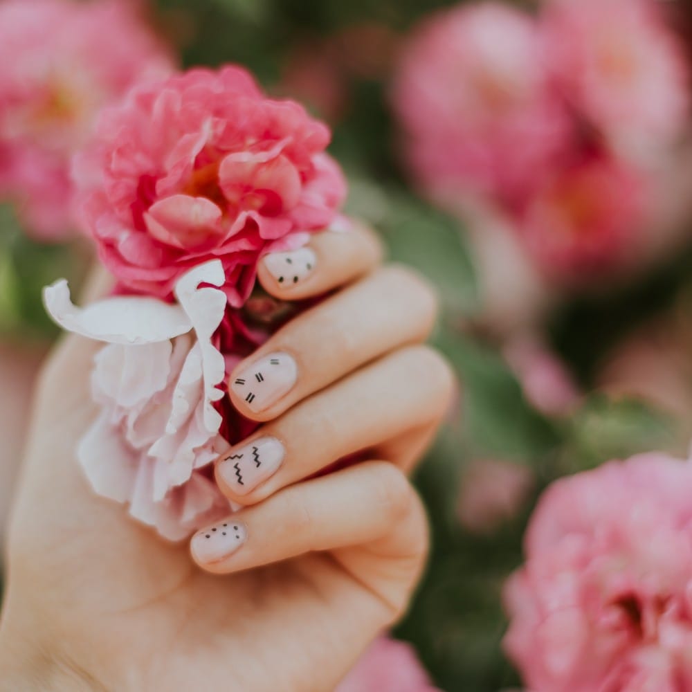 A woman touches a flower with her polygel nails.