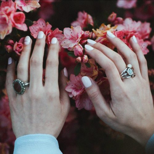A woman touches a flower with her acrylic nails.