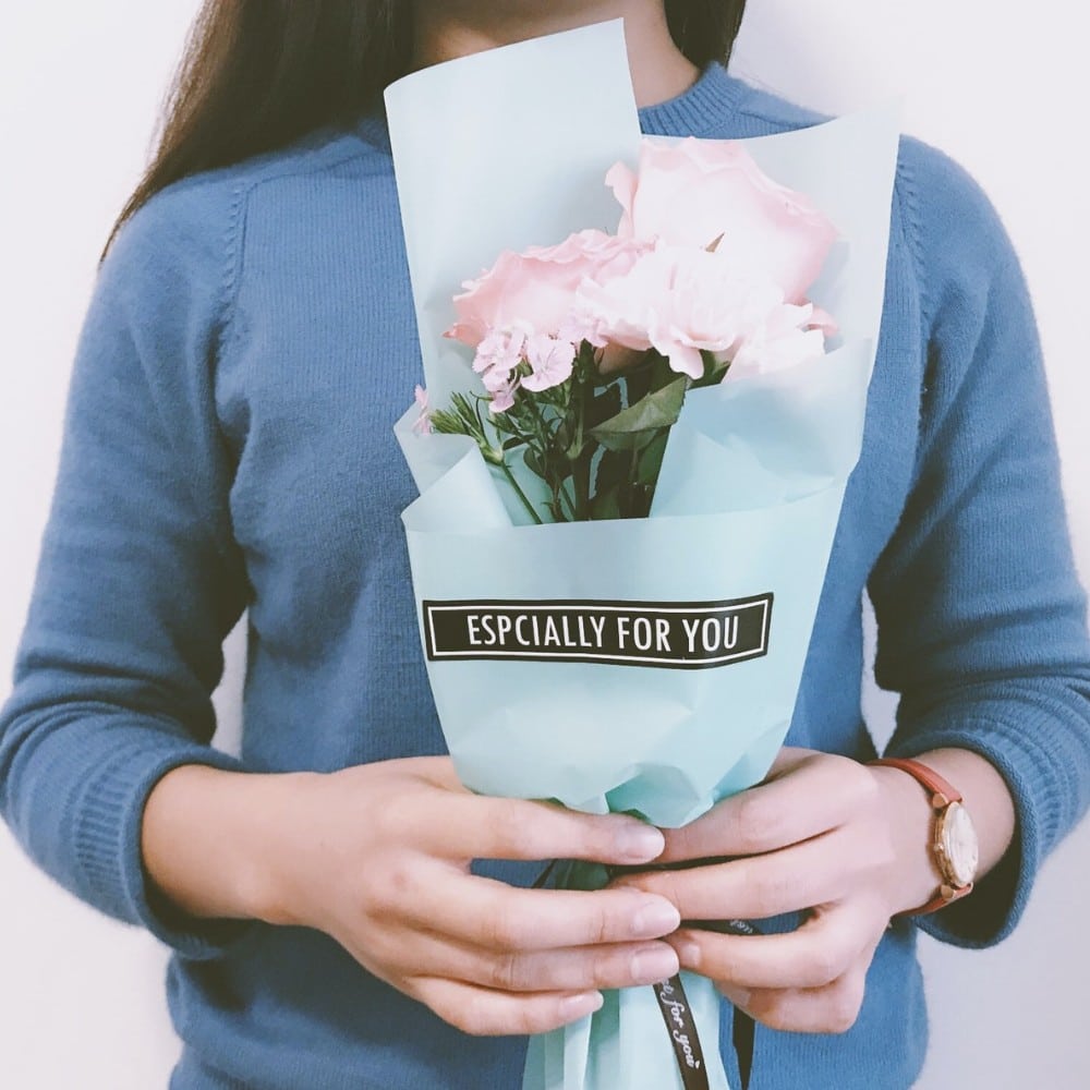 A woman is holding a bouquet of flowers in her hand. She has nice gel polish nails.